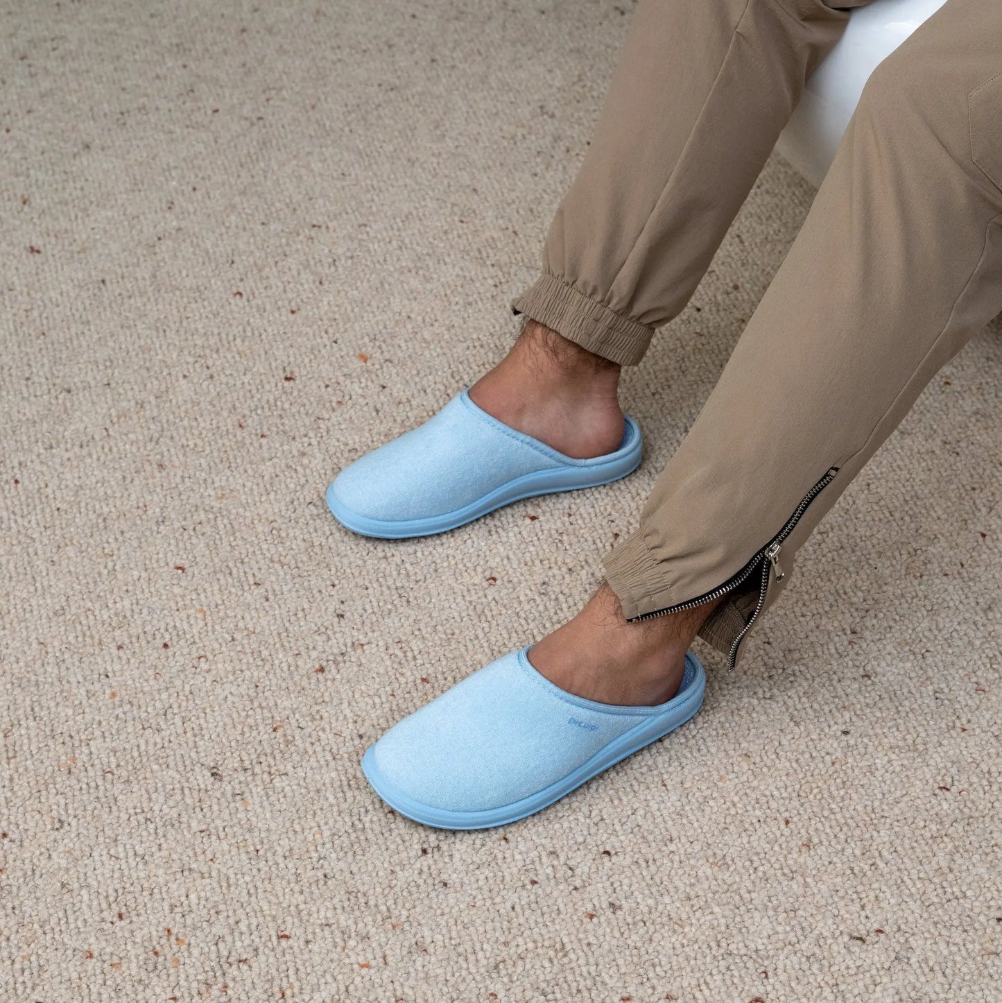 Man wearing DrLuigi® baby blue cotton medical slippers, seated pose