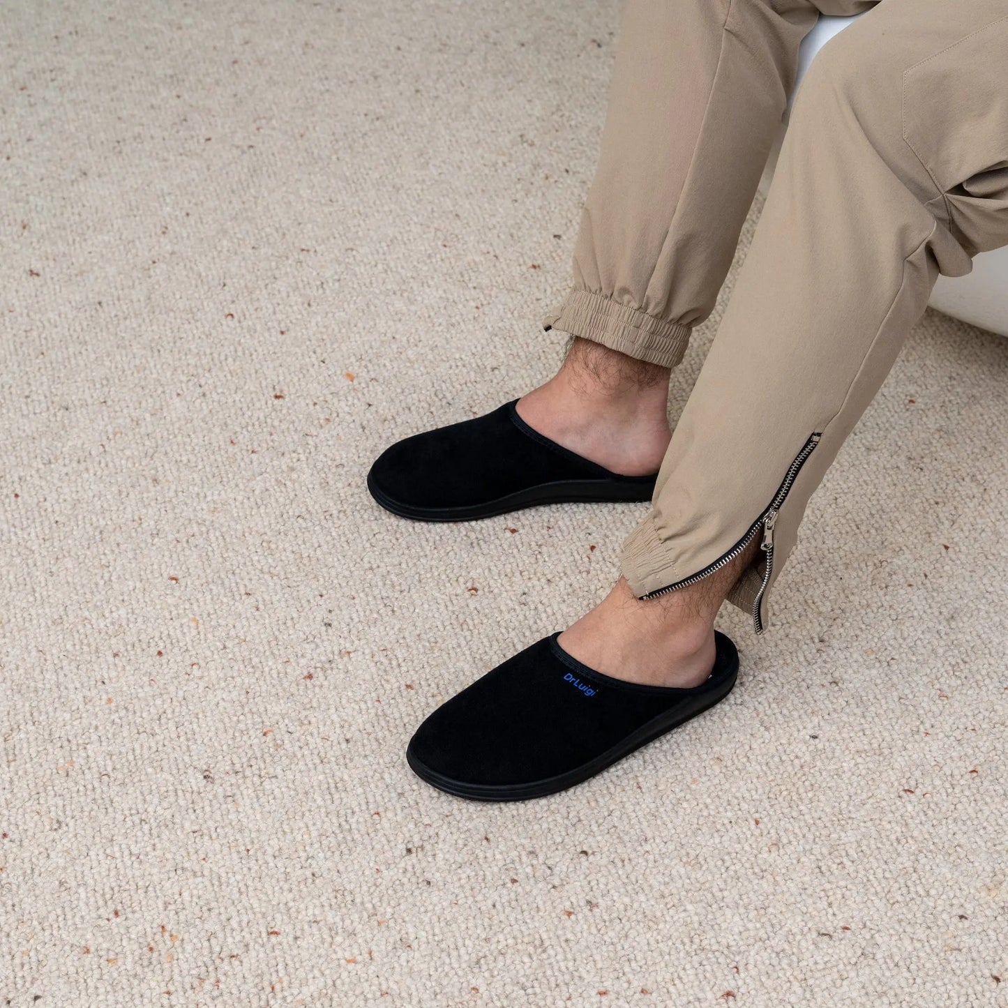 Man wearing DrLuigi® black cotton medical slippers, seated pose