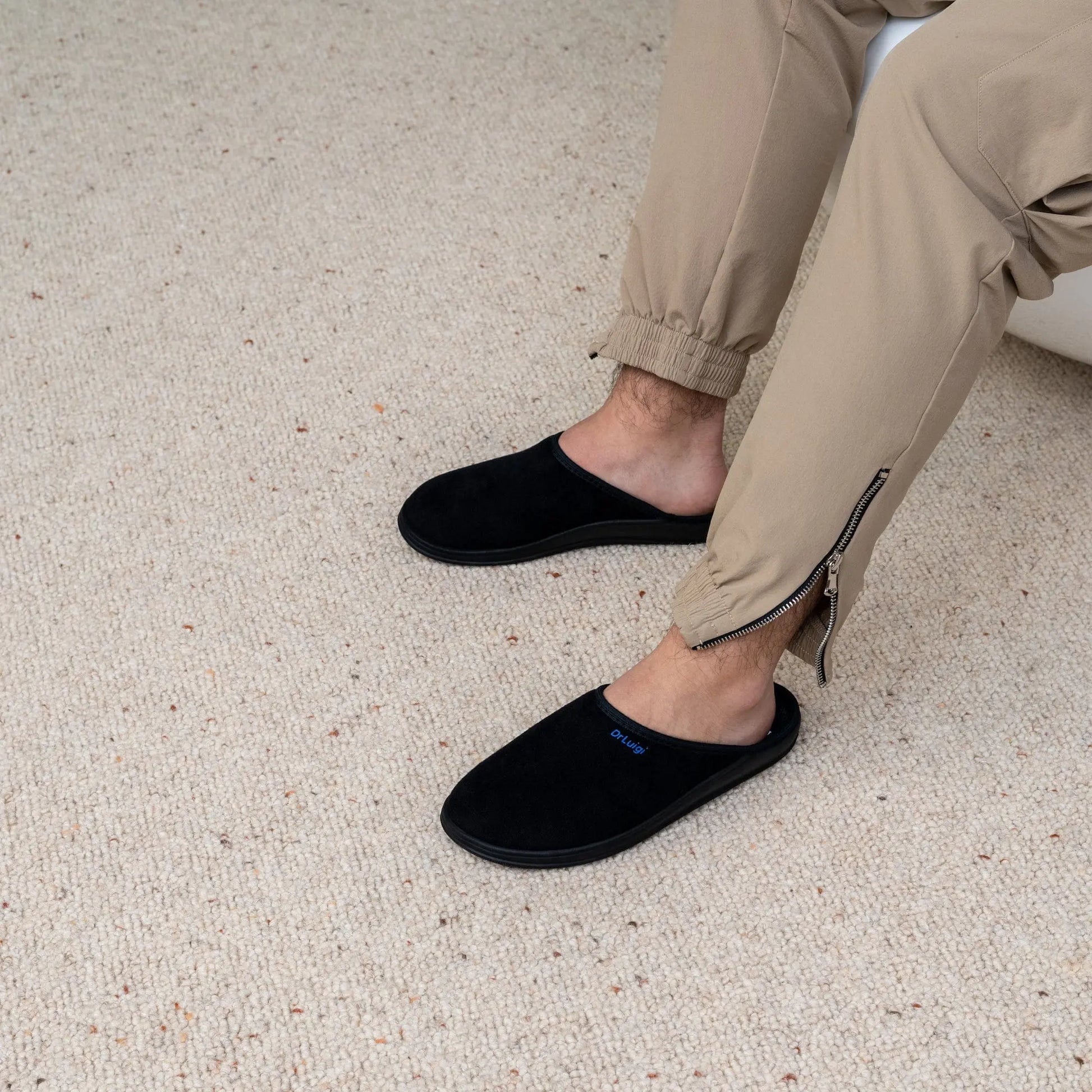 Man wearing DrLuigi® black cotton medical slippers, seated pose