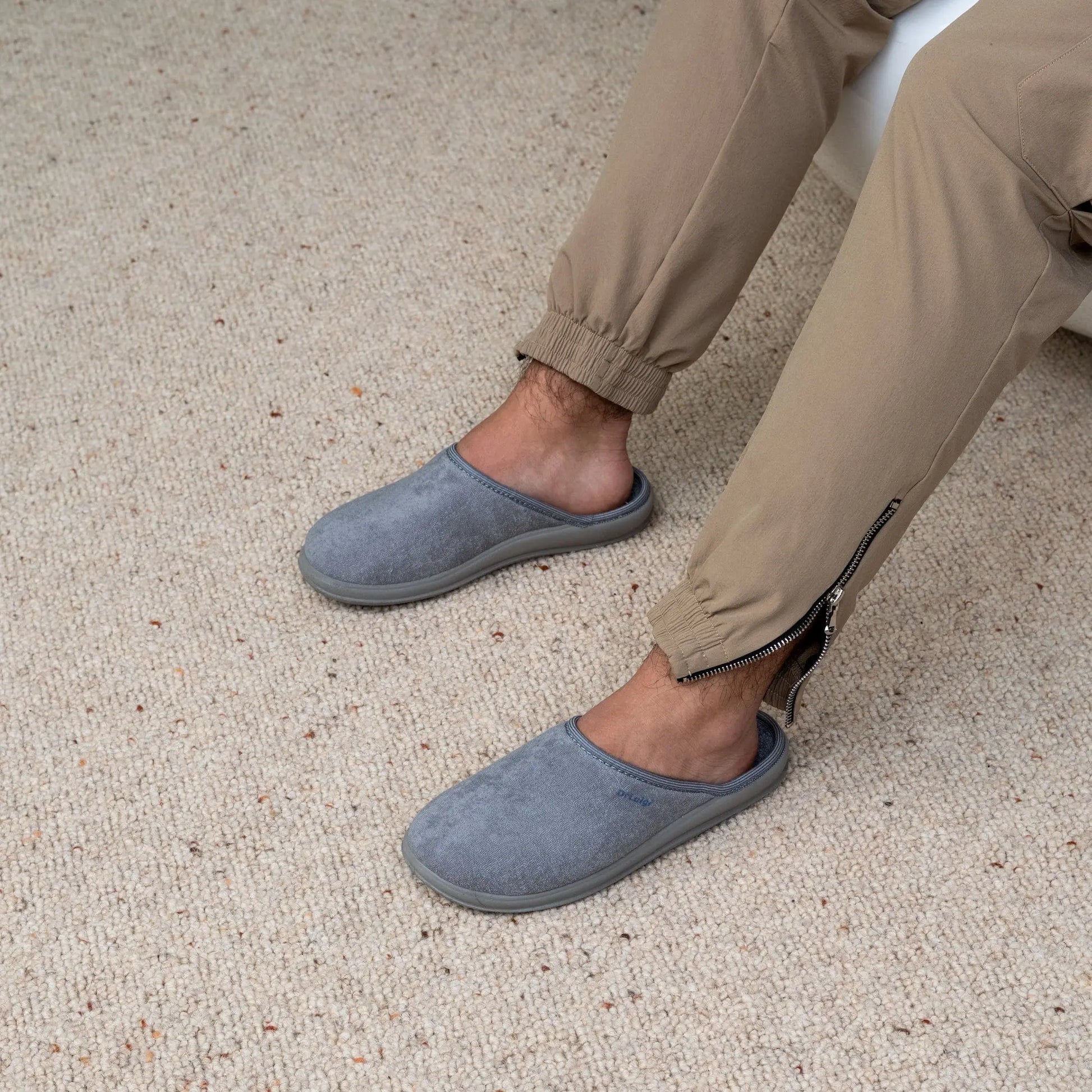 Man wearing DrLuigi® grey cotton medical slippers, seated pose