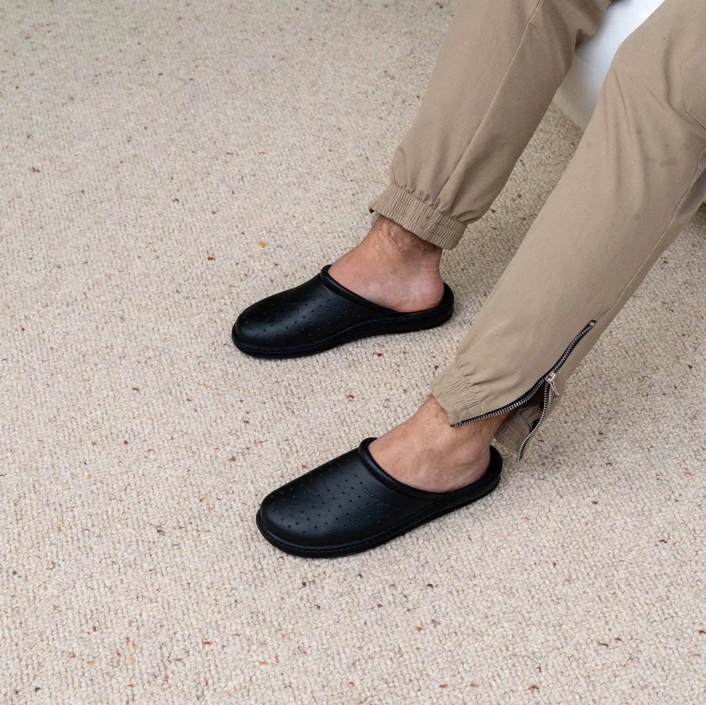 Man wearing DrLuigi® black leather orthopedic clogs, seated pose