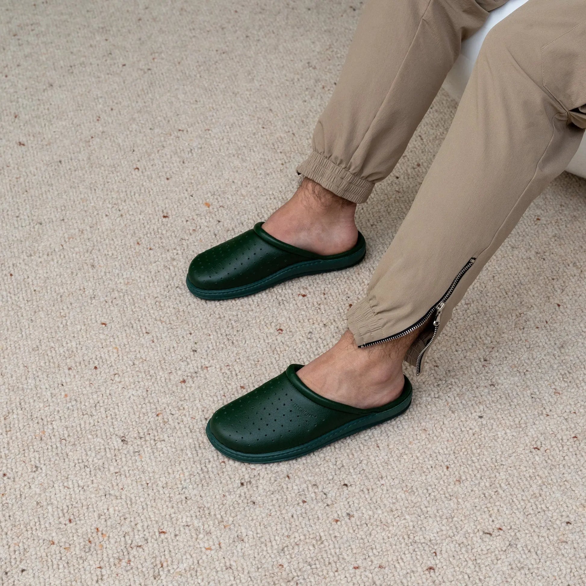 Man wearing DrLuigi® green leather orthopedic clogs, seated pose